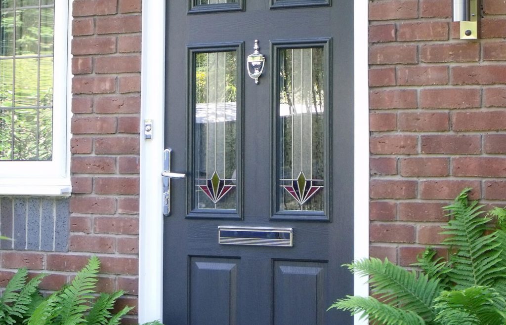 A dark grey front door with decorative glazed panels and chrome handle