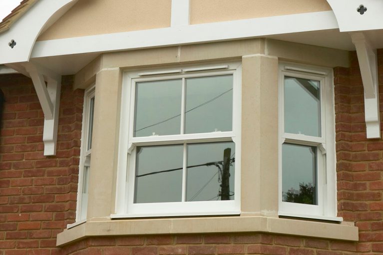 White UPVC bay vertical slider window with sash horns.