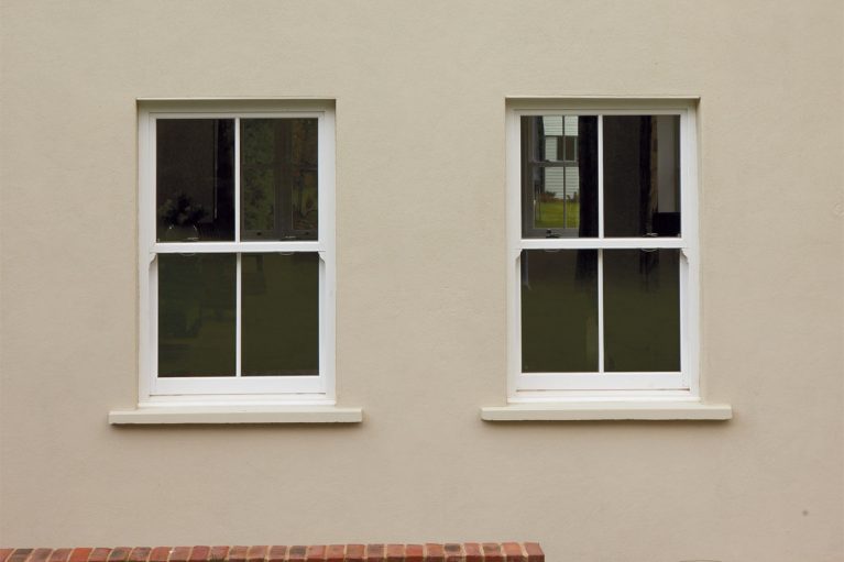 White UPVC vertical slider window with sash horns and window bars.