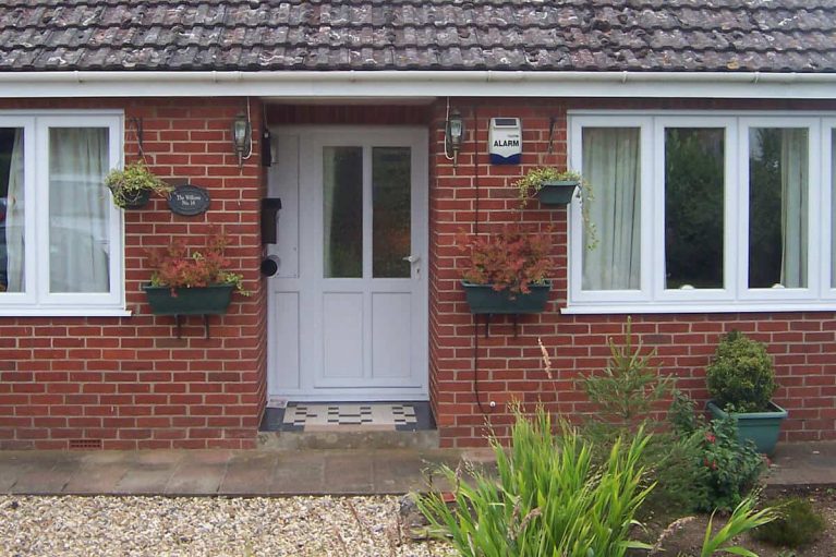 White upvc entrance door on red brick home